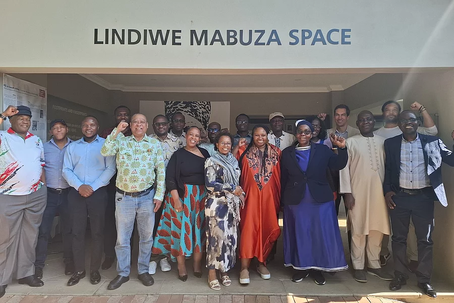A group of African Global Union Forum leaders pose for a photo outside the Lindiwe Mabuza Space at the Friedrich-Ebert-Stiftung office in Johannesburg. Several individuals in the photo are raising fists in a gesture of solidarity.