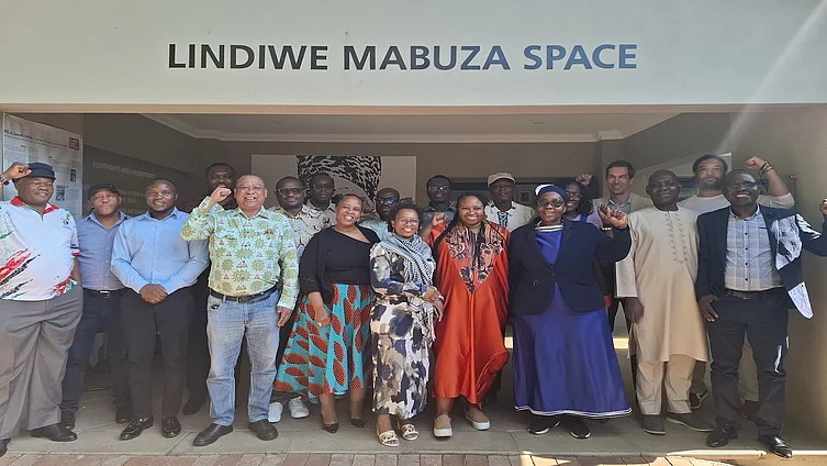 A group of African Global Union Forum leaders pose for a photo outside the Lindiwe Mabuza Space at the Friedrich-Ebert-Stiftung office in Johannesburg. Several individuals in the photo are raising fists in a gesture of solidarity.